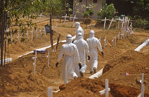 Agentes de saúde caminham por cemitério de vítimas de ebola na Libéria, em 2015