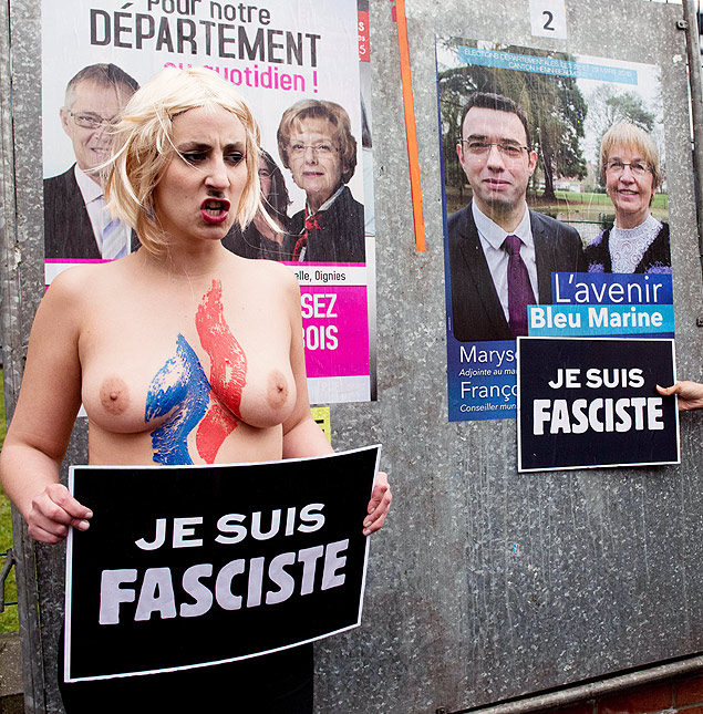 Ativista do grupo Femen protesta contra Marine Le Pen, da Frente Nacional; ela segura uma placa com os dizeres: 