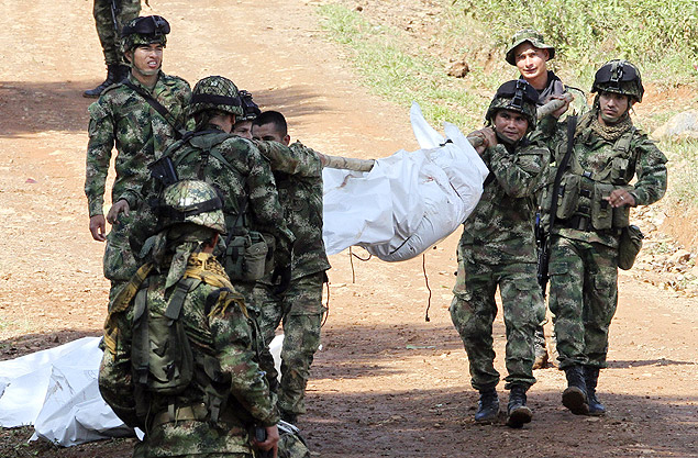Soldados colombianos carregam corpos de colegas de tropa que foram mortos em ataque das Farc