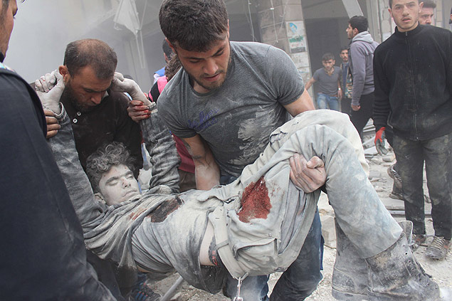 Sírios carregam corpo removido dos destroços de um prédio destruído em bombardeio do regime de Assad