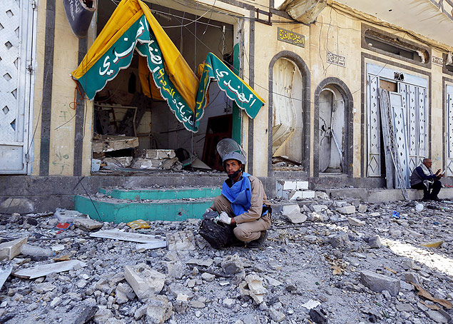 Agente iemenita observa local de bombardeio da coalizo liderada pelos sauditas em Sanaa