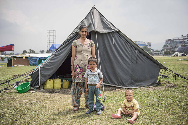 Uma me nepalesa e seus filhos em frente a uma cabana em Katmandu neste Dia das Mes