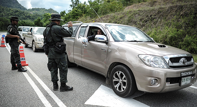 Policiais malaios inspecionam carros aps o governo anunciar a descoberta de valas comuns 