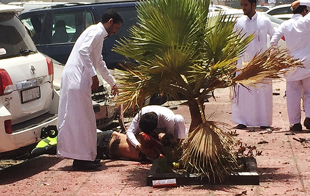 Fiis da mesquita xiita examinam corpo de um dos mortos no ataque ao templo nesta sexta-feira