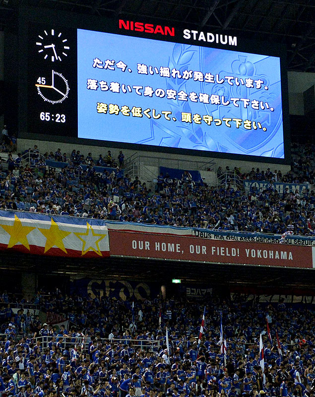 No telão de um estádio esportivo de Tóquio, um alerta avisa sobre o terremoto que atingiu o Japão
