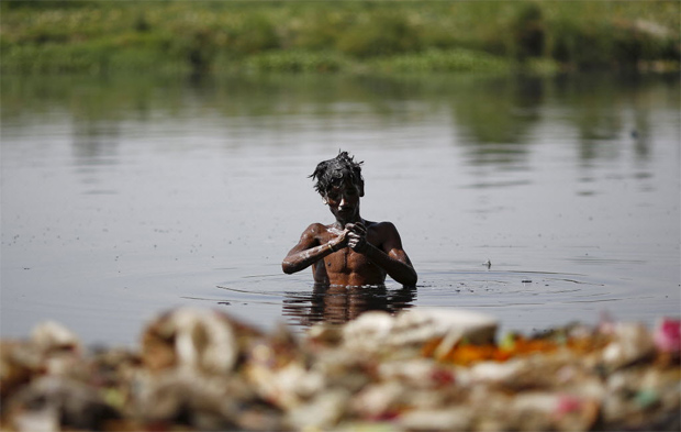 Homem se refresca no rio Ganges em D�li, no norte da �ndia