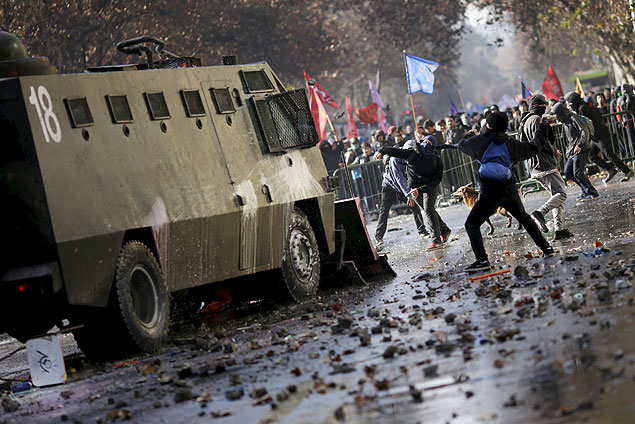Manifestantes atiram pedras em um veculo policial durante o protesto contra a reforma, no centro de Santiago 