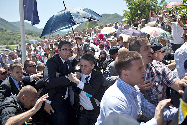 O premi srvio, Aleksandar Vucic (embaixo do guarda-sol, de culos), sai s pressas do memorial de Srebrenica aps vaias e ataques de pedras