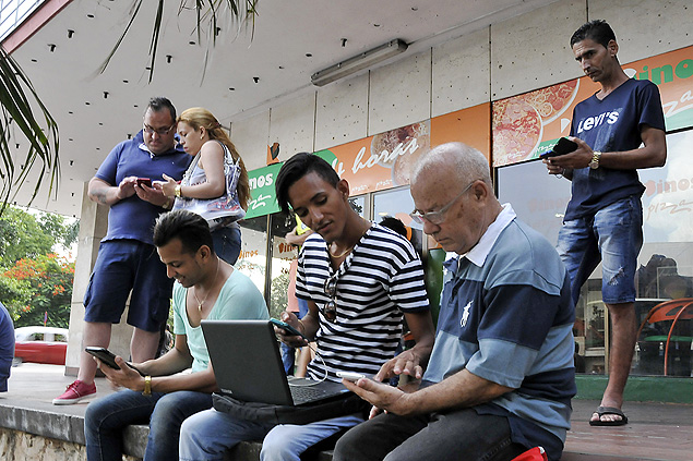 Cubanos usam laptops e celulares para tentar se conectar ao wi-fi pblico em Havana, capital do pas
