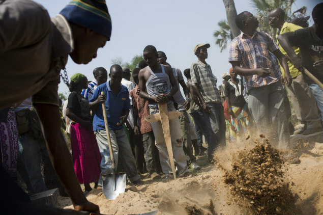 Homem enterra corpo do opositor Emmanuel Ndereyimana, assassinado, em Kimana