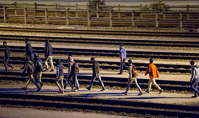 Imigrantes andam sobre trilhos no terminal do Eurotnel em Calais