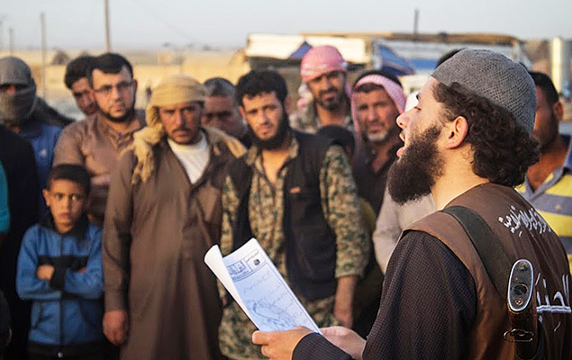 Imagem de maio de 2015 mostra integrante do Estado Islâmico Islamic State group's vice police known as "Hisba," right, reads a verdict handed down by an Islamic court sentencing many they accused of adultery to lashing, in Raqqa City, Syria. (Militant website via AP) ORG XMIT: NY609