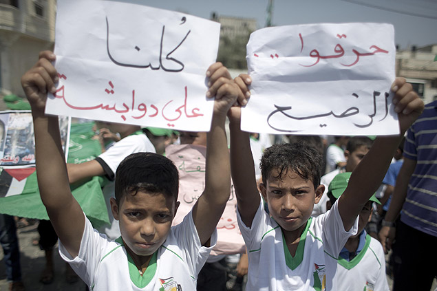 Crianas palestinas carregam placas com as frases "somos todos Ali Dawabsha" e "eles queimaram beb" em protesto no sul da faixa de Gaza 