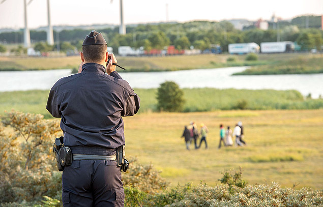 Policial francs filma imigrantes que tentam entrar no pas pelo Eurotnel, em Coquelles, perto de Calais