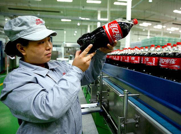 Operária inspeciona garrafa de Coca-Cola em fábrica em Shijiazhuang, na China