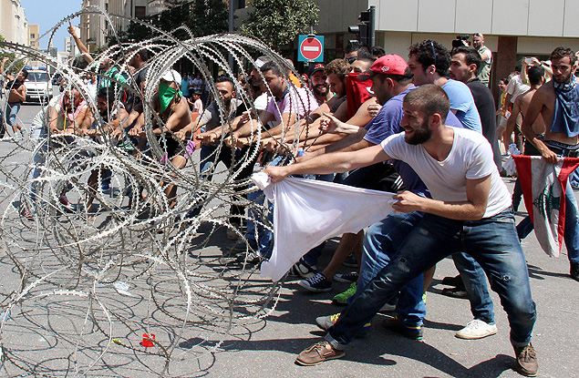 Ativistas libaneses tentam remover arame farpado que bloqueia a entrada do Palcio do Governo libans durante um protesto contra a crise do lixo
