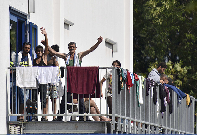 Imigrantes acenam em prdio usado como abrigo para refugiados na cidade de Heidenau, na Alemanha