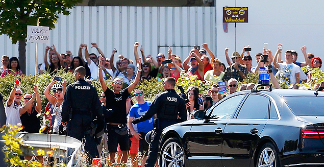 People hold a placard reading "Traitor" as German Chancellor Angela Merkel leaves after her visit to an asylum seekers accomodation facility in the eastern German town of Heidenau near Dresden, August 26, 2015 where last week more than 30 police were injured in clashes, when a mob of several hundred people pelted officers with bottles and fireworks. REUTERS/Axel Schmidt ORG XMIT: JOH18R