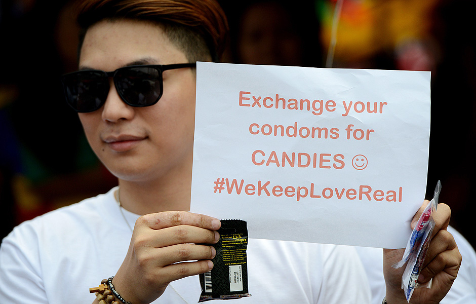 Em Manila (Filipinas), aps empresa local distribuir preservativos, ativista catlico segura cartaz onde se l: 'Troque seus preservativos por doces
