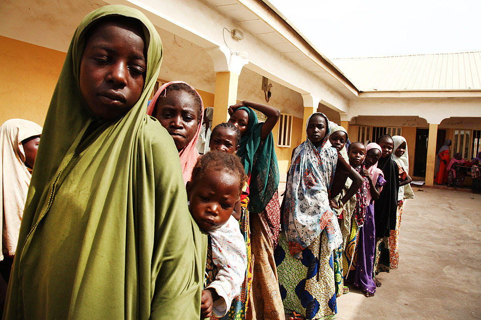 Meninas resgatadas do Boko Haram pelo Exército da Nigéria esperam para receber roupas em campo de refugiados no país