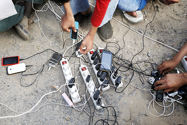 Migrantes do Afeganisto recarregam seus celulares em campo de Calais, na Frana
