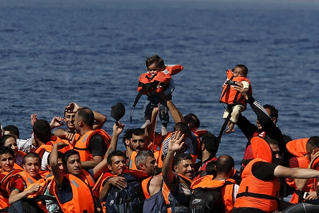 Refugiados srios mostram bebs com a aproximao de seu barco  ilha grega de Lesbos