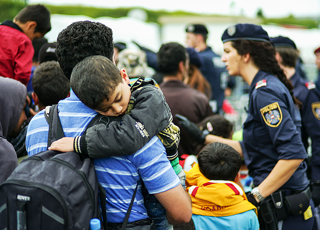 A migrant boy sleeps on the shoulder of a man after arriving at the border between Austria and Hungary near Heiligenkreuz, about 180 kms (110 miles) south of Vienna, Austria, Monday, Sept. 14, 2015. Austria's interior minister said the country will follow Germany in introducing border controls to manage the flow of people coming in from Hungary. (AP Photo/Christian Bruna) ORG XMIT: FOS109