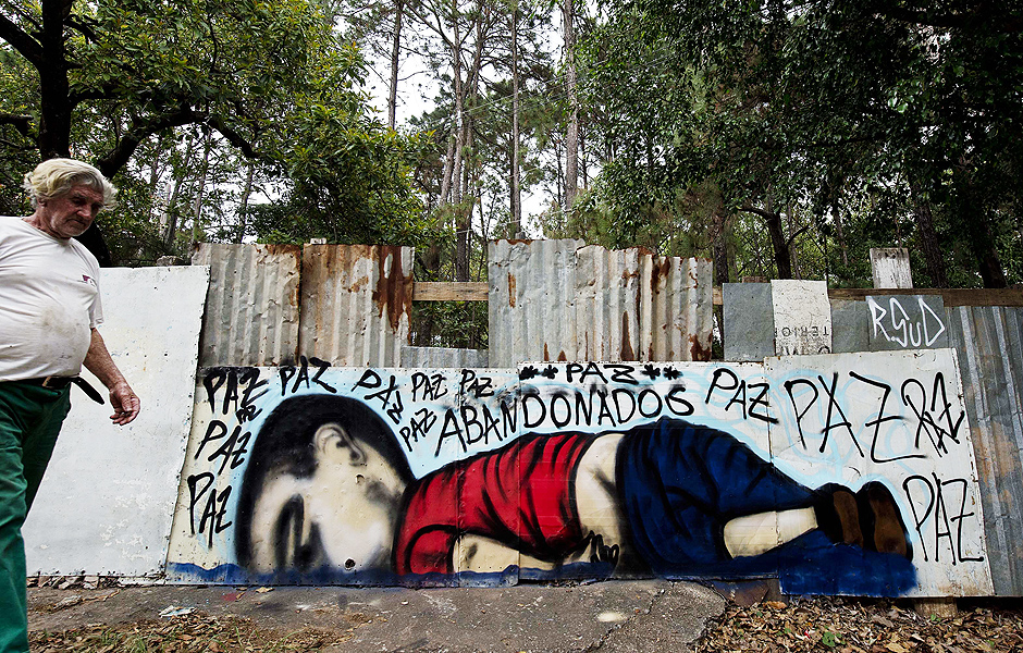 A man walks by a graffiti depicting Aylan Kurdi, also known as Aylan Shenu, a Syrian three-year-old boy whose drowning off a Turkish beach, in Sorocaba, some 90 km from Sao Paulo, Brazil, on September 6, 2015. AFP PHOTO / NELSON ALMEIDA ORG XMIT: SAO008