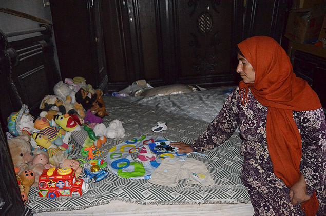 Fatma Mesto, 45, mostra roupas e brinquedos de seu neto, Alan, em quarto de sua casa em Kobani