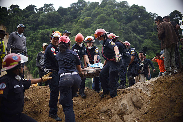 Bombeiros carregam corpo resgatado de sob os destroos em Santa Catarina Pinula, na Guatemala 