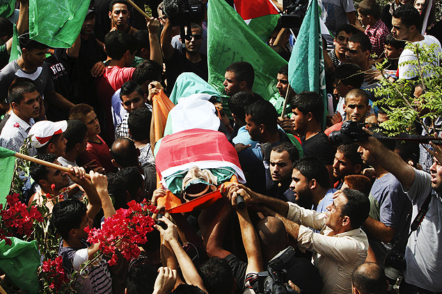 Palestinos carregam o corpo de um jovem de 18 anos morto no domingo por israelenses na Cisjordânia
