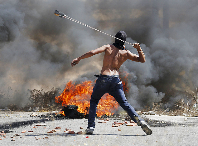 Manifestante palestino usa estilingue para atirar pedras contra militares israelenses perto de Ramallah