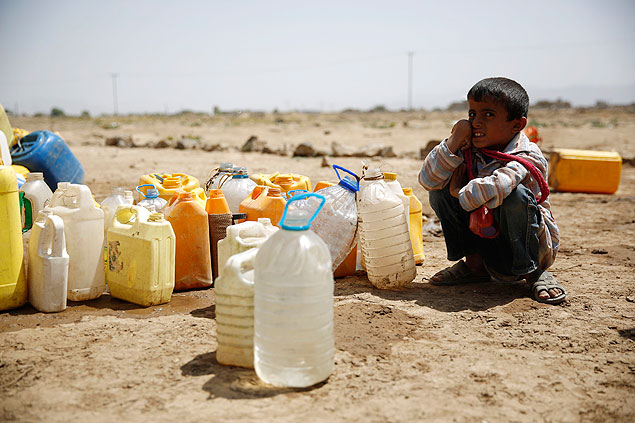 Menino espera sua vez para encher garrafas de água em na periferia de Sanaa
