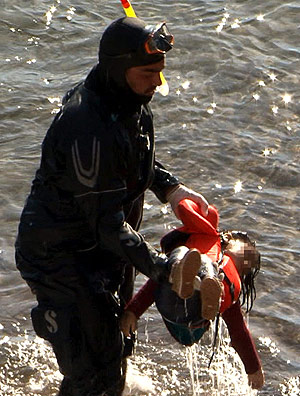 Mergulhador carrega corpo de menina que morreu afogada perto da ilha de Lesbos, na Grcia