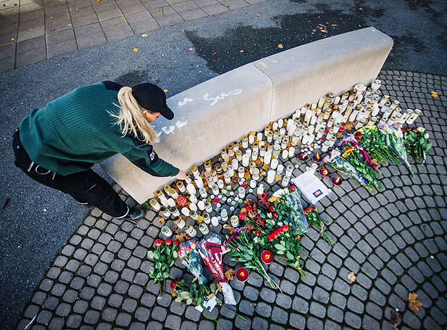 A woman lights candles outside a primary and middle school in Trollhattan, southwestern Sweden, on October 23, 2015, where a masked man armed with a sword yesterday killed two people before being arrested and shot by police. The killer, identified in the media as Anton Lundin-Pettersson, went from classroom to classroom at the school for six to 15-year-olds, which had many immigrants, in a attack confirmed by investigators as a "racially motivated" hate crime. AFP PHOTO / JONATHAN NACKSTRAND ORG XMIT: 6250
