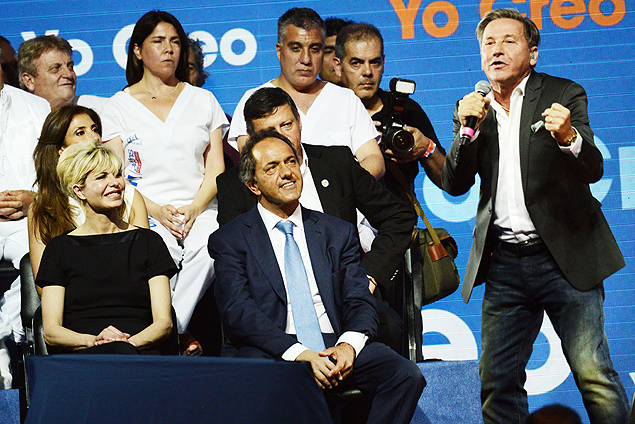 Buenos Aires governor and presidential candidate for the ruling Frente para la Victoria (Front for Victory) party, Daniel Scioli (C), and his wife Karina Rabolini (L), look at Argentine-born Venezuelan singer Ricardo Montaner (R) as he performs during the closing rally of the campaign in Buenos Aires, on October 22, 2015. General elections will be held on October 25 in Argentina. AFP PHOTO/Eitan Abramovich ORG XMIT: EAS312