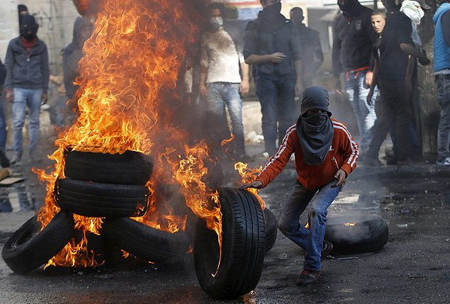 Manifestante palestino ateia fogo em pneus durante protesto contra as foras israelenses em Hebron