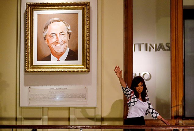 A presidente Cristina Kirchner acena para apoiadores ao lado de retrato do marido, Nstor (1950-2010) 