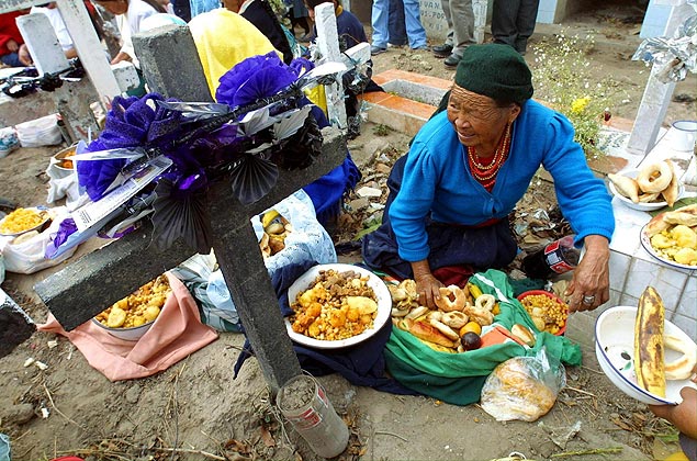 ORG XMIT: 473301_1.tif Comemorao do Dia dos Mortos, em Quito, Equador: Una indigena sentada junto a la tumba de un familiar, sirve comida a sus parientes conmemorando el dia de los muertos, en el cementerio de Calderon en las afueras de Quito, el 2 de noviembre de 2001. Cientos de personas se acercaron al cementerio donde prepararon y comieron diversos platos tipicos, tradicion que se remonta a la epoca de los incas. AFP PHOTO/MARTIN BERNETTI - Finados 