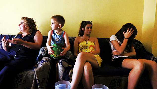 Anthoula Papazoi (L) reacts as she sits beside her son Anastasis (2nd L), 5, and daughters Elli (2nd R), 16, and Nikoleta, 13, at their home in the city of Ioannina, Greece July 10, 2015. Picture taken July 10, 2015. To match Special Report GREECE-TEETH/ REUTERS/Cathal McNaughton ORG XMIT: PXP401