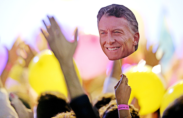 Eleitor segura retrato de Mauricio Macri, eleito novo presidente da Argentina neste domingo (22)