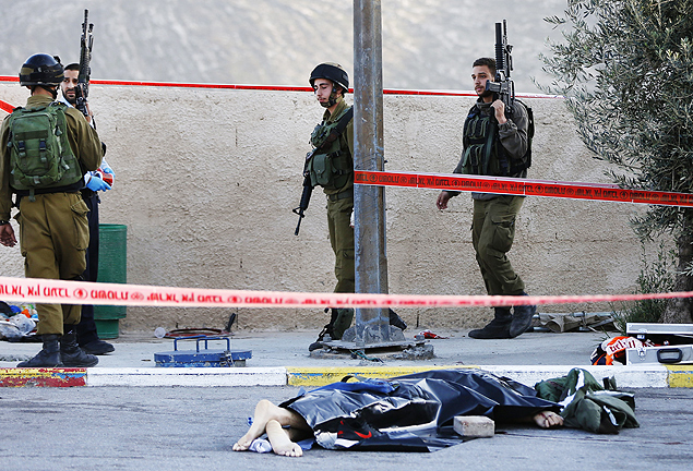 Soldados israelenses fazem guarda ao lado do corpo de um palestino morto aps matar israelense