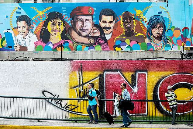 Pedestres passam em frente a grafite que retrata Hugo Chvez e Nicols Maduro, em Caracas