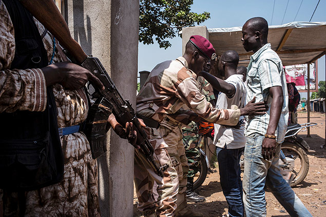 Soldados da Repblica Centro-Africana revistam homens na entrada de centro de votao