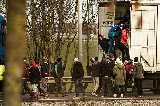 Refugiados e imigrantes entram em caminho perto de Calais, na Frana, para tentar chegar  Inglaterra