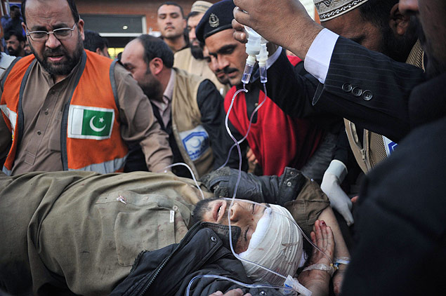 Pakistani paramedic transport a bomb blast victim to a hospital in Peshawar on December 29, 2015. At least 21 people were killed and dozens wounded when a Taliban suicide bomber on a motorbike crashed into the main gate of a government office in the northwest Pakistan town of Mardan, officials said. AFP PHOTO / Hasham AHMED ORG XMIT: PK337