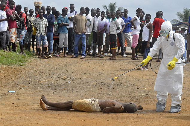 Funcionário da área de saúde desinfecta homem moribundo vítima do ebola em Monróvia, na Libéria