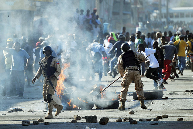 Policiais haitianos tentam apagar pneus em chamas aps confronto com manifestantes em Porto Prncipe 