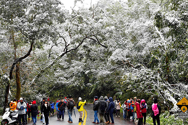 Turistas tiram fotos da neve na montanha Yangming, em Taip, Taiwan