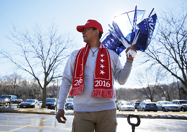 O vendedor Anthony Winthrop segura bandeiras de Donald Trump em evento de campanha em Iowa